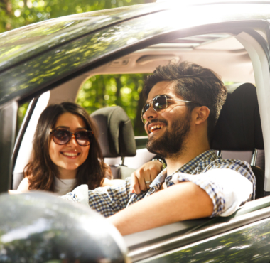 A happy young couple is in their car bought with an auto loan.