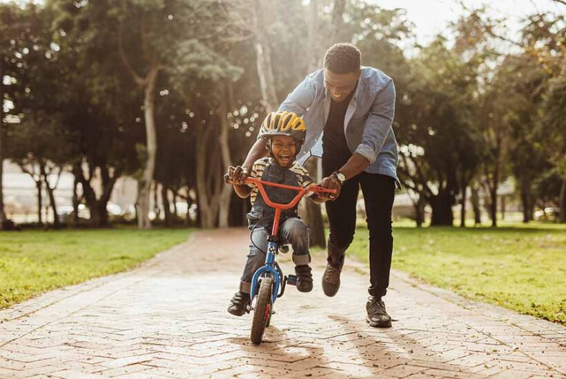 A man teaching his son how to ride a bike in the Pacific Northwest.