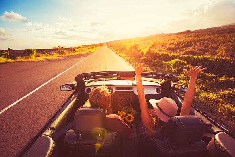 A couple drives into the sunset after getting a great auto loan rate on a convertible.