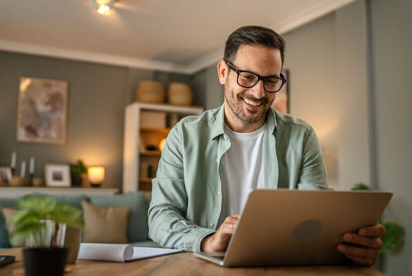 A man looking at America's Credit Union savings account rates on his computer.